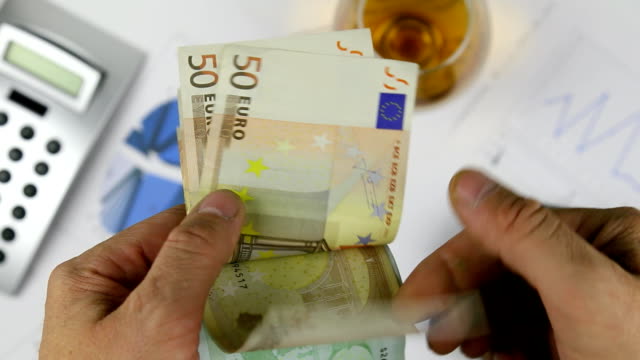 Man-counting-european-paper-money,-euros-on-the-background-of-a-diagram-and-a-cigar