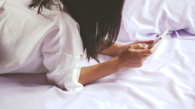 Asiatische-Frau-Festlegung-auf-Bett-mit-Smartphone-in-der-hand-spielen-Gameand-Film-online,-Technologie-mit-Menschen-Konzept-Hintergrund