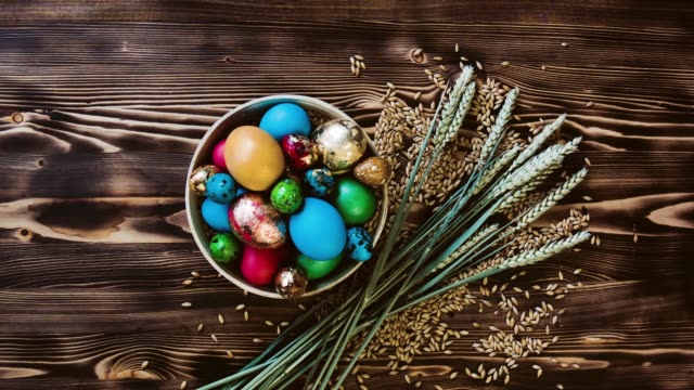 Hermosos-huevos-de-Pascua-se-encuentran-en-tazón-de-fuente-de-madera-en-mesa-de-madera.