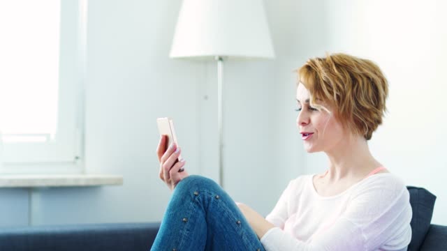 woman-sitting-on-a-gray-sofa-and-chatting-video