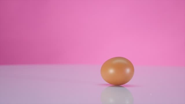 Das-Ei-dreht-sich-auf-einem-Tisch-auf-einem-rosa-Hintergrund
