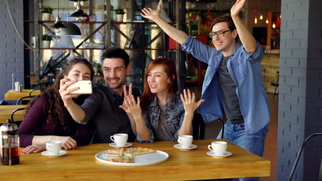 Emotionale-Jugendliche-nehmen-Selfie-mit-Smartphone-posieren-und-Lachen-im-modernen-Café.-Moderne-Technologie,-Freundschaft,-Spaß-und-Millennials-Konzept.