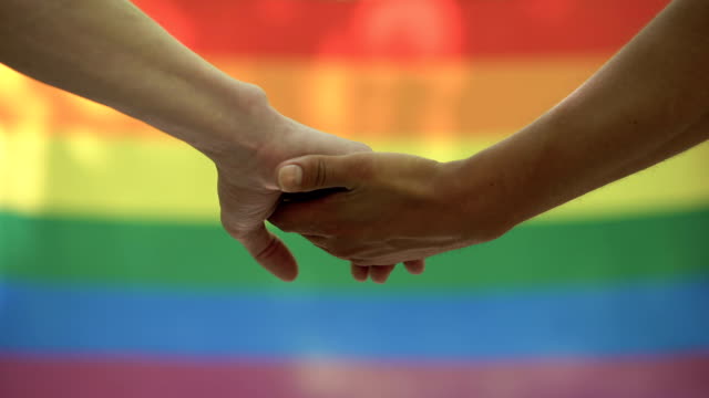 Gay-stroking-partner-hand-lgbt-flag-background,-rights-equality-pride-march