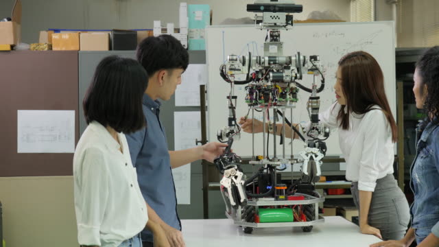 Junge-Elektronik-Ingenieur-Team-gemeinsam-an-der-Konstruktion-des-Roboters-in-der-Werkstatt.-Team-Ingenieur-Inbetriebnahme-für-Roboter-Projekt-zusammen.-Menschen-mit-Technologie-oder-Innovation-Konzept.