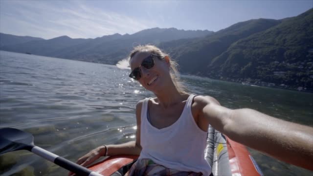 Joven-tomando-retratos-selfie-en-canoa-roja-montaña-lago-una-mujer-disfruta-vacaciones-de-verano-tener-diversión-en-actividades-al-aire-libre---lenta