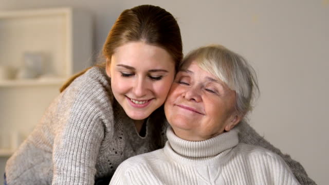 Enkelin-glücklich-umarmt-behinderte-Frau-im-Rollstuhl,-Familienwerte-zu-lieben