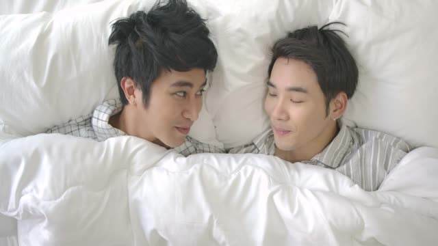 Gay-couple-in-bed-making-love-under-white-blanket.-People-with-gay,-homosexual,-relationship-concept.