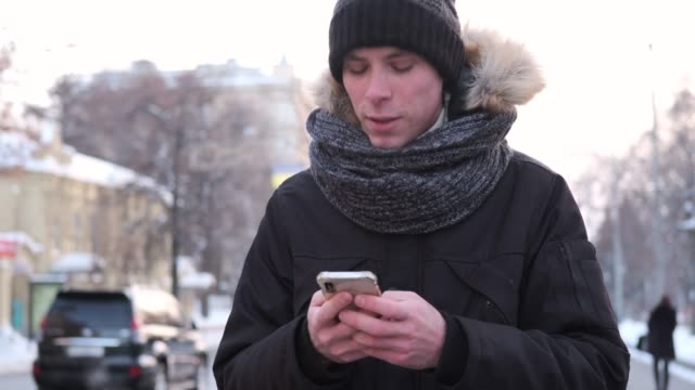 Man-walking-and-using-mobile-phone-on-a-cold-winter-day