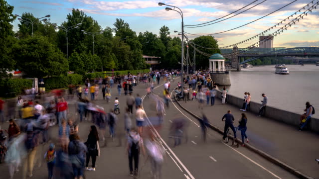 crowds-of-people-walk-along-the-embankment-of-a-city-river,-time-lapse