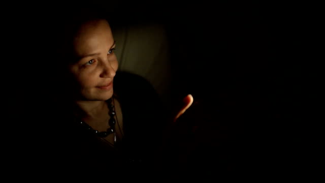 a-middle-aged-Caucasian-woman-sitting-at-night-in-a-room-on-the-couch-with-a-smartphone-and-communicates-with-friends-on-social-networks