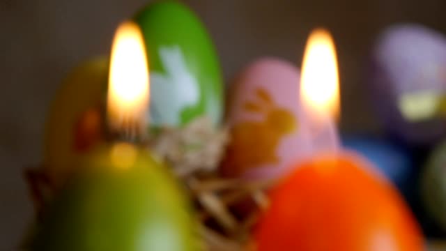 Kerzen-in-Form-von-Osterei.-Grün,-orange,-gelb.-Ostereier-Kerzen-und-bunte-Ostereier-im-Hintergrund.-Fokus-und-Neufokussierung.