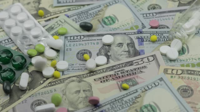 Pills-falling-on-dollar-banknotes,-expensive-medication,-pharmaceutical-business
