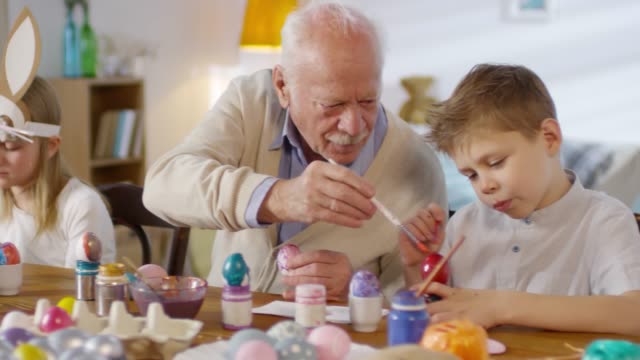 Grandfather-Playing-with-Grandson-while-Painting-Eggs