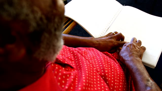 Mittelteil-des-blinden-Seniorenmanns,-der-ein-Braille-Buch-im-Pflegeheim-4k-liest
