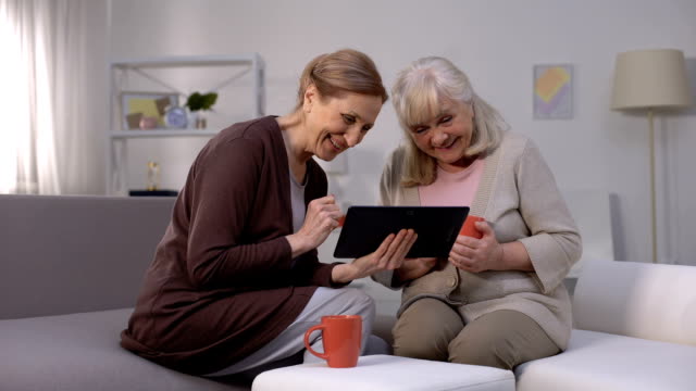 Ältere-Frauen-lächeln,-beobachten-Unterhaltungsshow-auf-Tablet,-schnelles-Internet