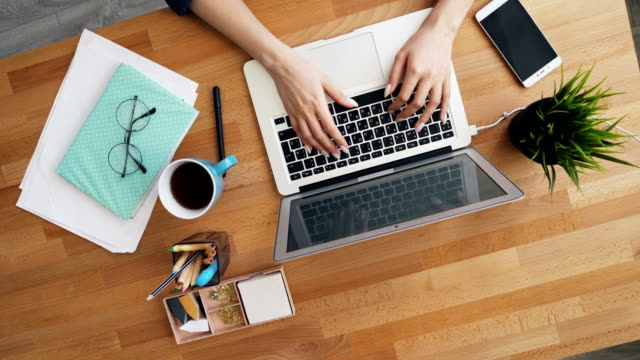 Manos-femeninas-escribiendo-usando-computadora-portátil-en-la-oficina-comunicándose-en-el-trabajo