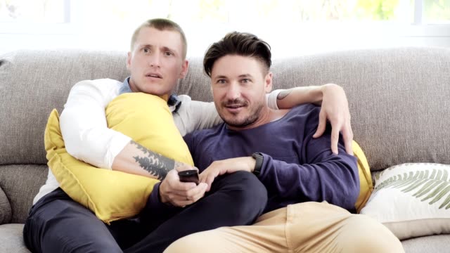 Gay-couple-relaxing-on-couch.-Enjoy-watching-tv,-teasing.
