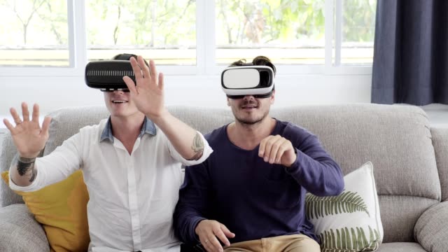 Schwules-Paar-entspannen-auf-der-Couch-mit-Virtual-Reality-Gerät.-Blick-in-die-VR-Welt.
