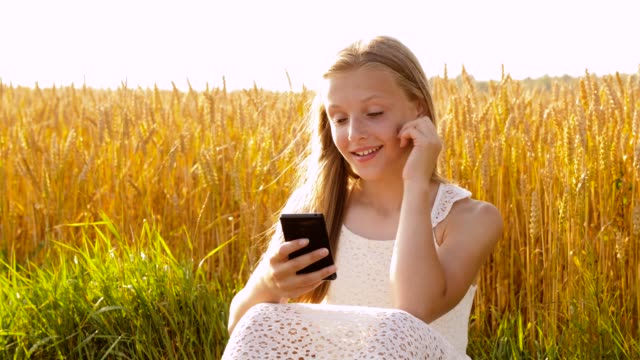 glücklich-junge-Mädchen-mit-Smartphone-auf-Getreidefeld