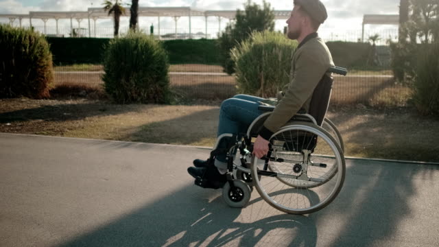 Hombre-independiente-discapacitado-se-está-moviendo-sentado-en-silla-de-ruedas-sobre-la-calle