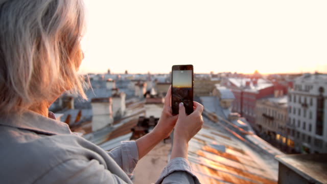 Grauhaarige-Frau-macht-Fotos-auf-dem-Dach