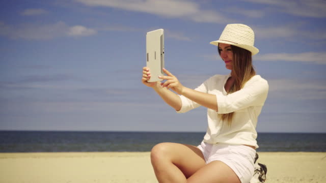 Chica-relajándose-en-la-playa-tomando-auto-foto-con-tableta-4K
