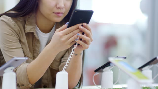 Asiatische-Frau-testet-Mobiltelefone