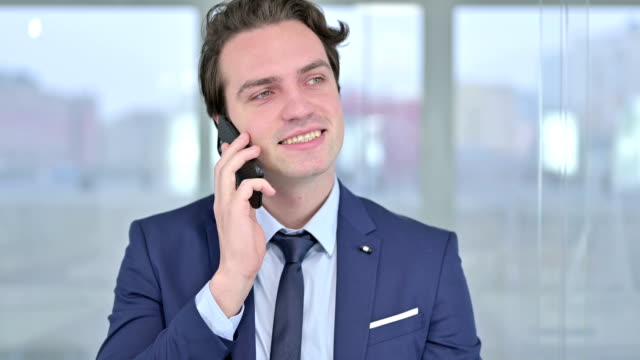 Porträt-des-fröhlichen-jungen-Geschäftsmannes,-der-auf-dem-Smartphone-spricht