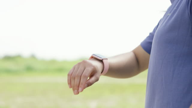 Sportliche-Frau-mit-Smart-Watch-Überprüfung-der-Herzfrequenz-beim-Training-läuft-im-Freien.