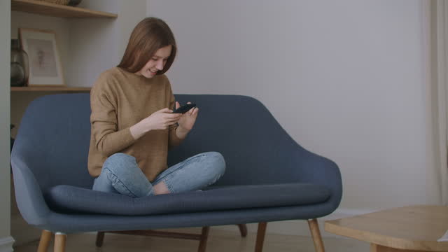business-woman-typing-message-on-mobile-phone-at-home-office.-Young-girl-chatting-on-phone-in-slow-motion.-Close-up-young-woman-hands-using-smartphone-on-couch.