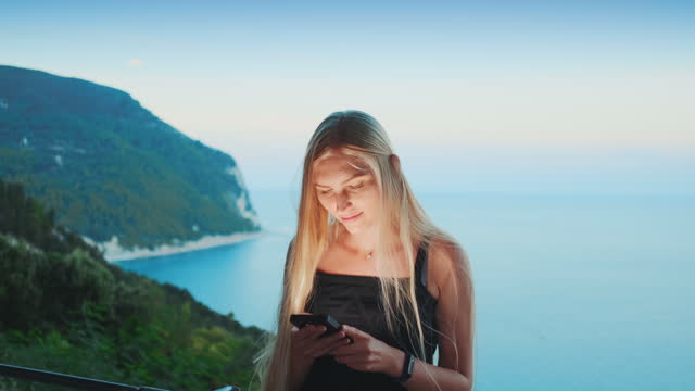 Mujer-usando-el-teléfono-inteligente-con-el-océano-en-el-fondo
