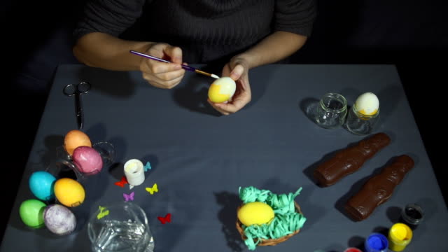 Mujer-manos-de-pintura-de-la-decoración-del-huevo-de-Pascua-sobre-un-fondo-gris.