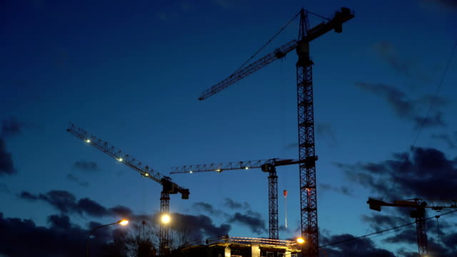 Concept-teamwork,-crane-as-symbol-new-life-and-changes-in-night-city.-Spotlight-light-construction