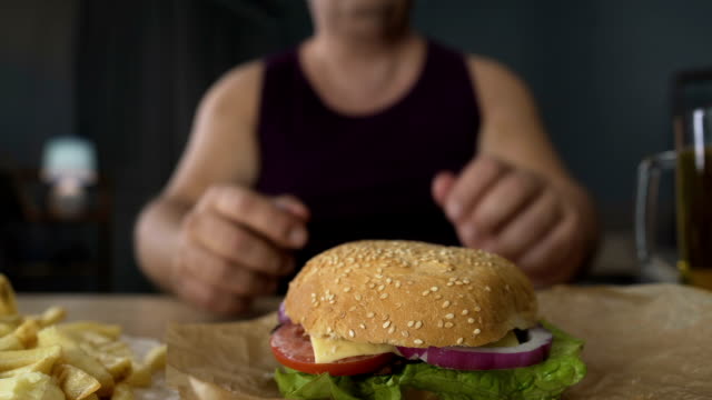 Übergewichtige-Menschen-beißen-große-Burger-Stück,-übermäßiges-Essen-in-der-Nacht,-Adipositas