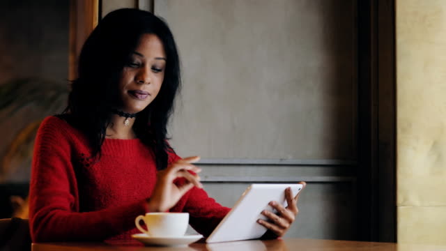 Woman-using-tablet-pc-drinking-coffee-in-cafe