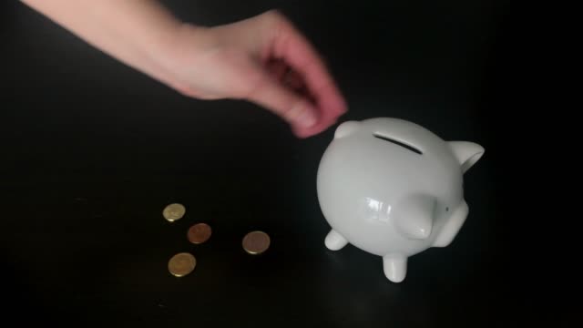 Woman-putting-Euro-coins-into-a-piggy-bank