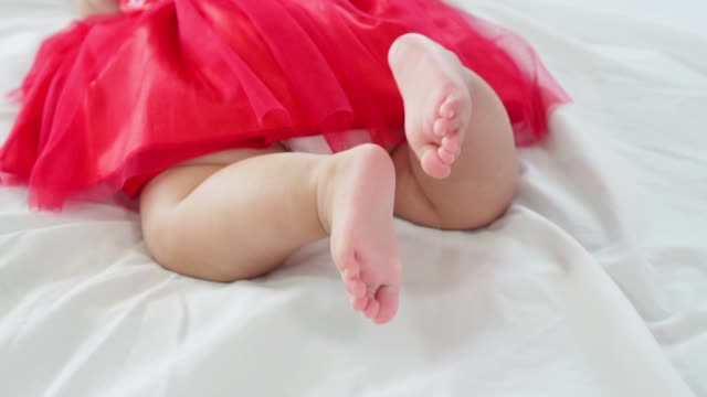 Baby-Mädchen-auf-dem-Bauch-liegend-und-schwingen-ihre-Beine-um-zu-versuchen,-in-Zeitlupe-erschossen-kriechen