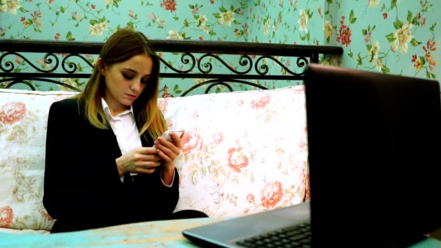 Girl-typing-on-a-smartphone,-in-front-of-a-laptop