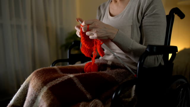 Senior-woman-sitting-in-wheelchair-and-knitting,-pleasurable-hobby,-close-up