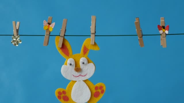 The-Easter-bunny-is-hanging-on-the-clothesline-on-blue-background.