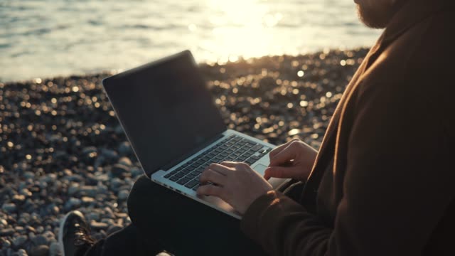Moderner-Autor-tippt-auf-Tastatur-des-Notebooks-im-Hintergrund-des-Meeres-Flut