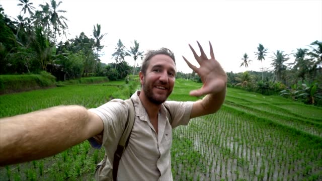 Hombre-joven-viajando-en-Asia-tiene-un-selfie-usando-su-cámara-junto-a-la-terraza-de-los-campos-de-arroz-en-Bali,-Indonesia.
