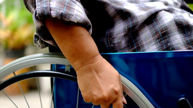 Hands-of-a-female-patient-turning-wheels-on-wheelchair-for-move-forward