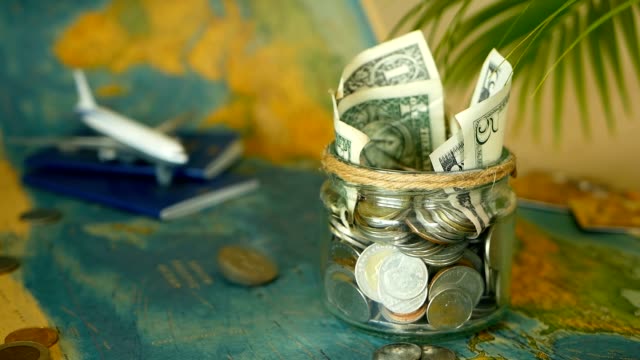 Travel-budget-concept.-Money-saved-for-vacation-in-glass-jar-on-world-map-background