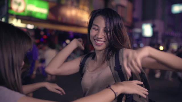 Cámara-lenta---pareja-de-lesbianas-lgbt-de-Asia-las-mujeres-viajero-mochilero-bailando-juntos.-Consumo-de-alcohol-o-cerveza-con-los-amigos-y-tener-parte-en-el-camino-de-Khao-San-en-Bangkok,-Tailandia.