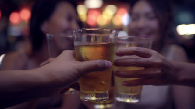 Cámara-lenta---pareja-de-viajero-mochilero-mujeres-asiáticas-lesbianas-lgbt-viaje-en-Bangkok,-Tailandia.-Consumo-de-alcohol-o-cerveza-con-los-amigos-y-tener-parte-en-el-camino-de-Khao-San.