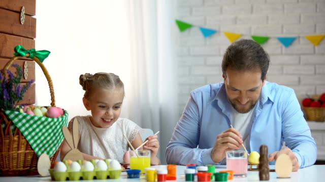 Glückliche-Tochter-und-Vater-Spaß-Malerei-gegenseitig-mit-Pinsel,-Ostern