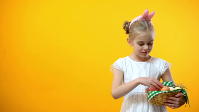 Glückliches-Ostern-Text,-entzückende-Schülerin-unter-rosa-Ei-aus-Korb-Grußkarte