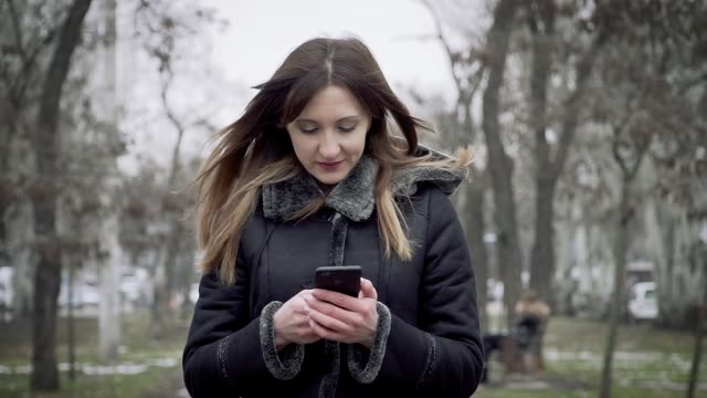Mujer-joven-va-con-el-teléfono-móvil-y-se-comunica-en-la-red-social-en-cámara-lenta