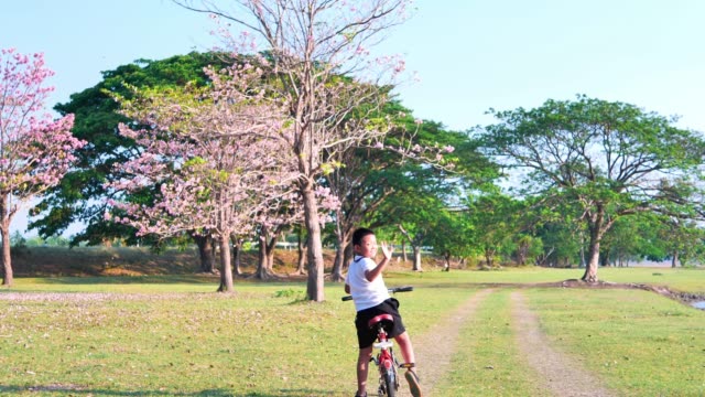 Eine-dicke-asiatische-Frau-joggt-abends-in-natürlichem-Sonnenlicht,-zusammen-mit-seinem-Sohn,-der-mit-dem-Fahrrad-unterwegs-ist.--Für-gute-Gesundheit.